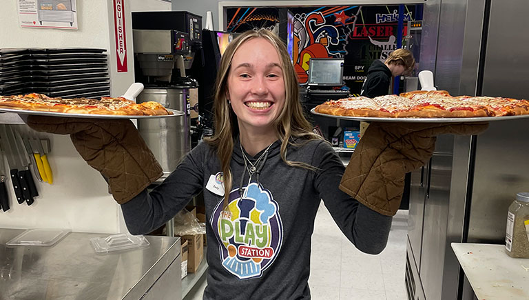 Female Employee Holding Two Pizzas